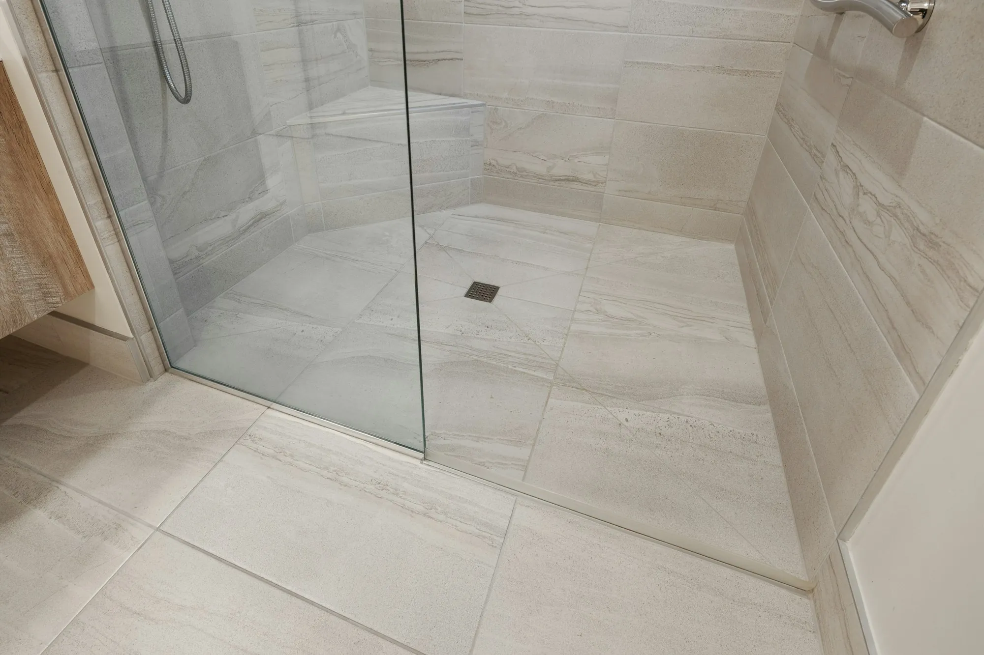 Curbless walk-in shower with a glass panel and large-format tile