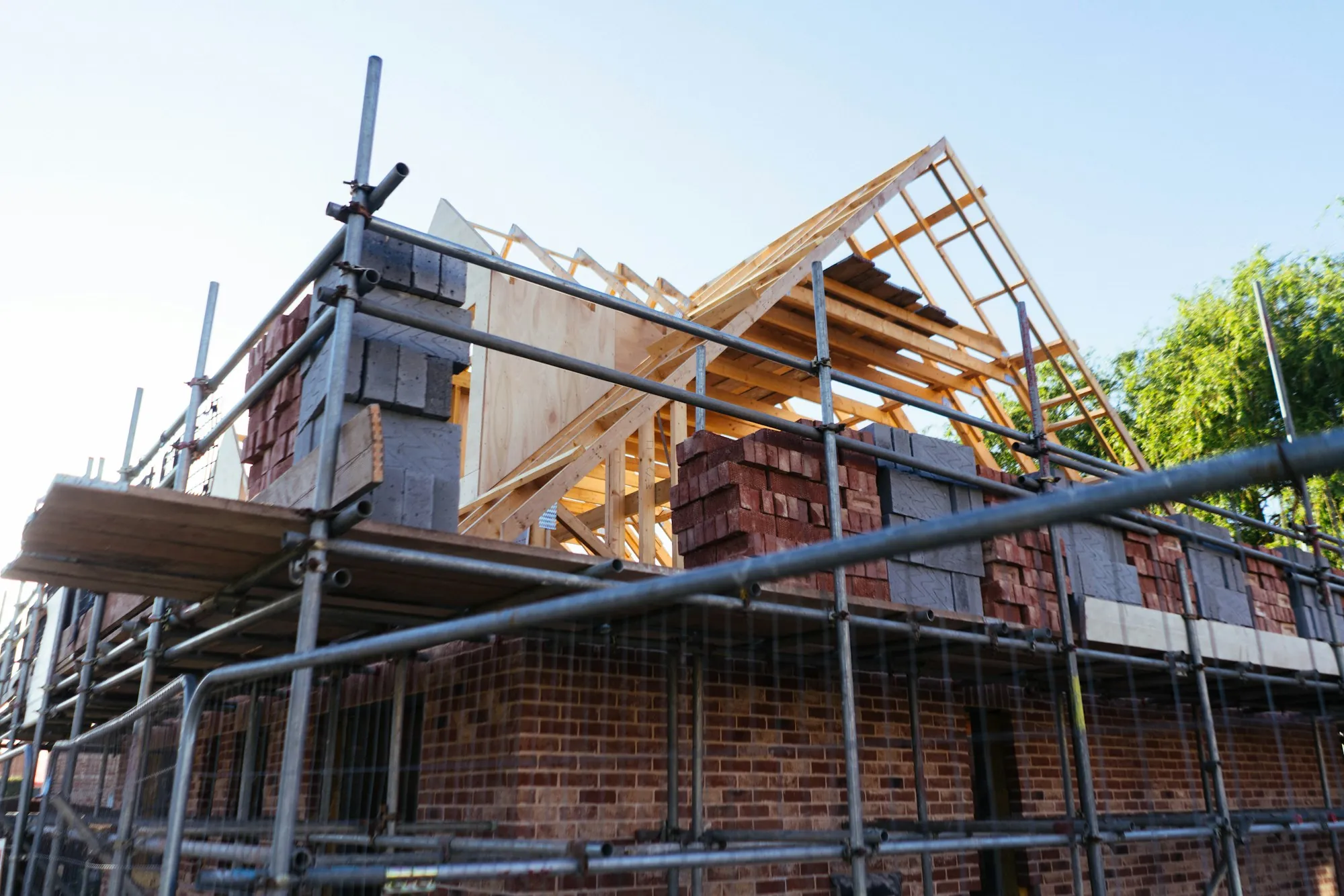 Brick addition under construction with scaffolding and new roof framing