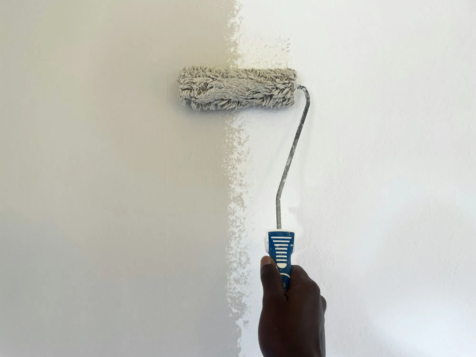 Paint roller applying a fresh coat of white paint to a wall